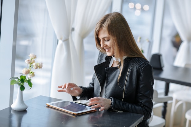 Sourire femme assise dans un restaurant de toucher une tablette