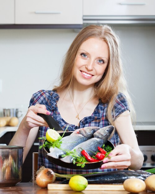 Sourire, femme blonde, cuisiner, lubina, frire, poêle