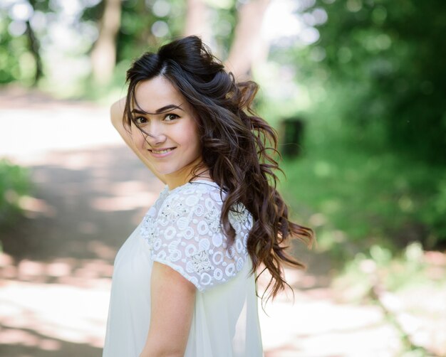 Sourire femme brune en robe blanche pose dans le jardin