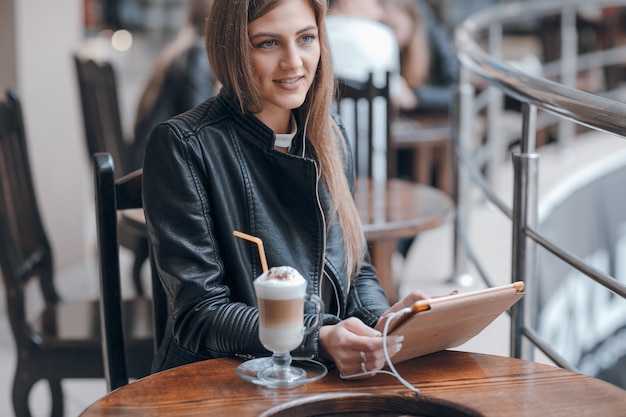 Sourire femme avec un casque blanc et un smoothie sur la table