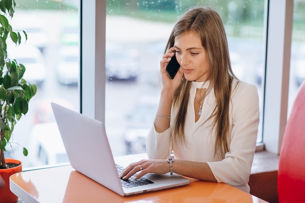 Photo gratuite sourire femme élégante de parler sur le téléphone et l'écran de son ordinateur