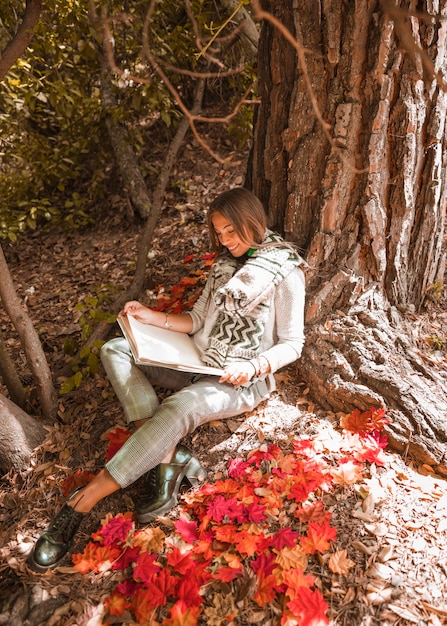 Sourire femme lisant dans la forêt d'automne