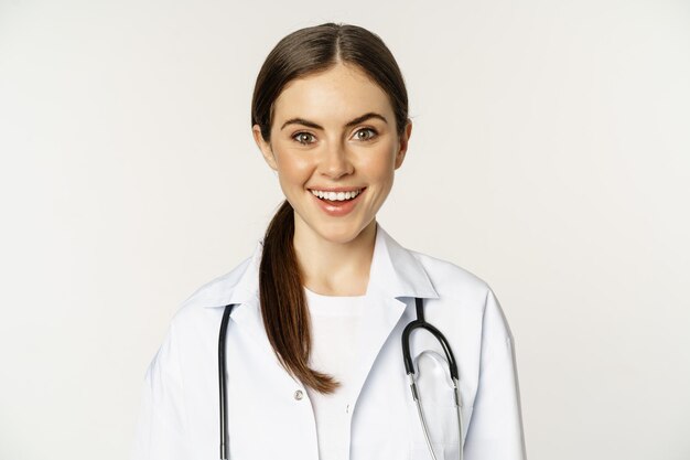 Sourire femme médecin médecin au rendez-vous à l'air heureux et confiant portant un manteau blanc et ste...