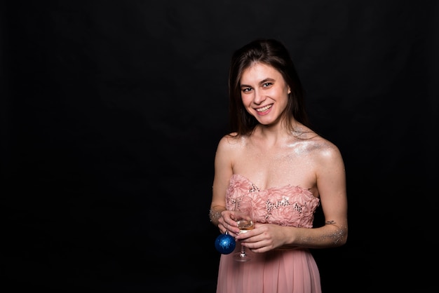 Sourire femme en robe de soirée avec verre et boule d&#39;ornement