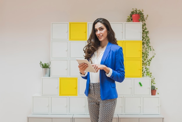 Sourire femme avec tablette et casiers de fond