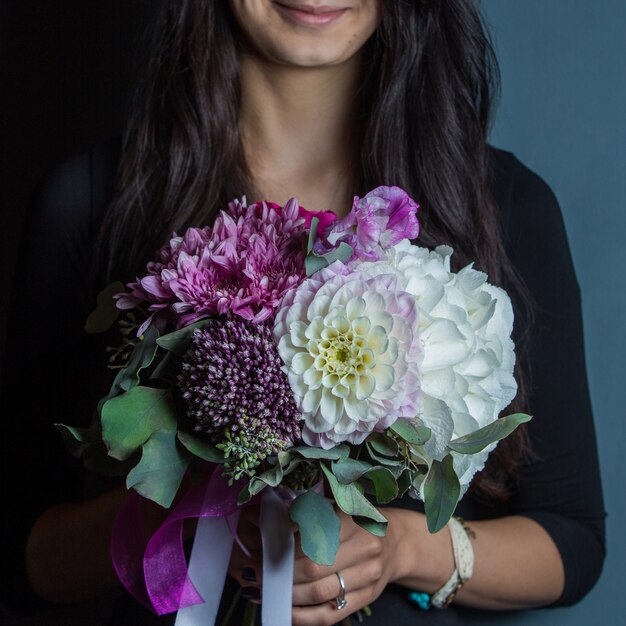 Sourire femme tenant un bouquet de fleurs mix blanc et violet