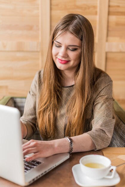 Sourire femme travaillant avec un ordinateur portable dans un café