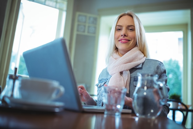 Sourire, femme utilisant un ordinateur portable tout en ayant du café