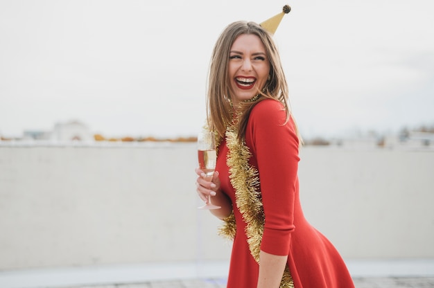 Sourire femmes en robe rouge tenant un verre de champagne