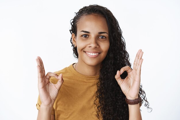 Sourire fille afro-américaine aux cheveux bouclés montrant bien, geste d'approbation