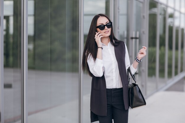 Sourire fille avec des lunettes de soleil parlant sur son téléphone