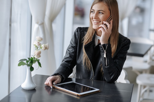 Sourire fille parlant sur le téléphone assis dans un restaurant