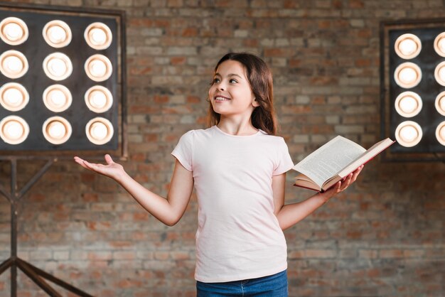 Sourire fille répétant en studio tenant un livre ouvert