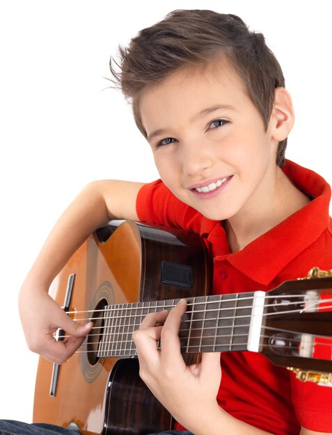 Sourire garçon caucasien joue à la guitare acoustique isolé sur blanc