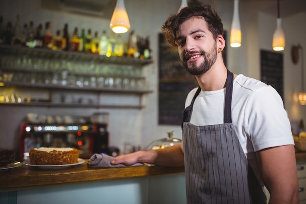 Sourire garçon essuyant comptoir avec serviette en cafÃ ©