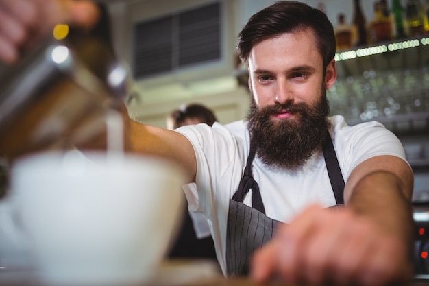 Sourire garçon faisant tasse de café au comptoir