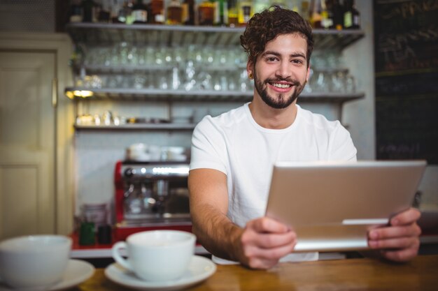 Sourire garçon utilisant tablette numérique au comptoir de café ©