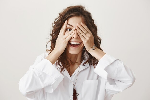 Sourire heureux anniversaire fille en attente de surprise avec les yeux fermés, furtivement à travers les doigts