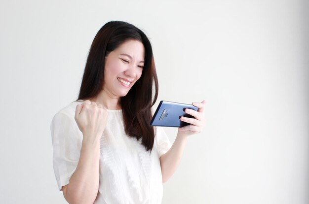 Sourire heureux femmes asiatiques à la recherche de succès sur smartphone et gagnant sur les achats en ligne