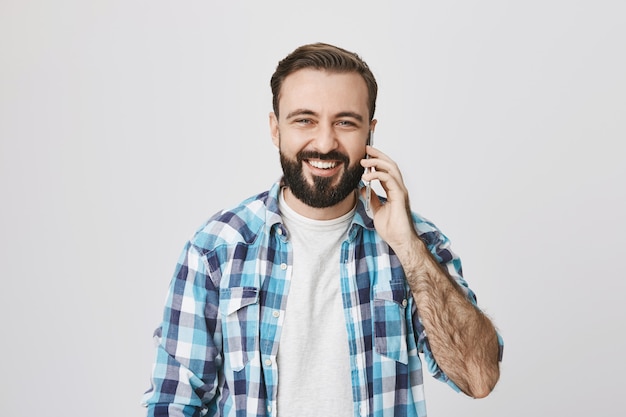 Sourire heureux homme adulte parlant au téléphone