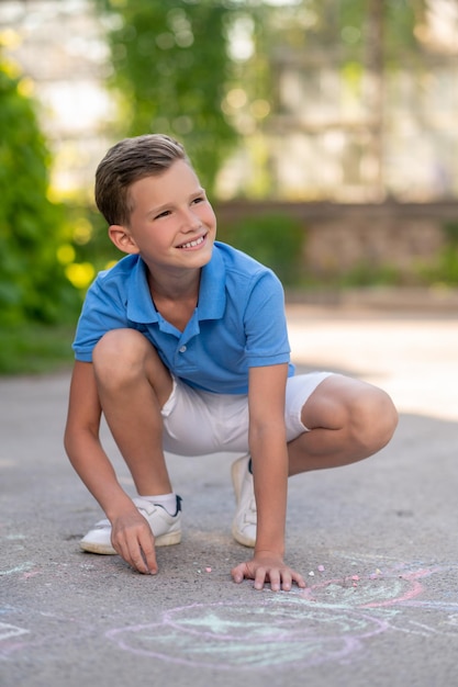 Sourire heureux jeune garçon impliqué dans le processus créatif