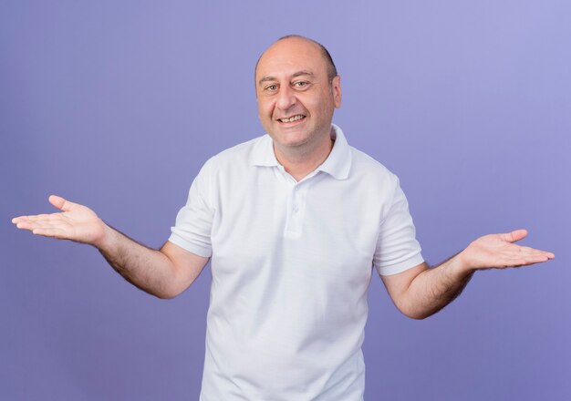 Sourire homme d'affaires mature occasionnel montrant les mains vides isolés sur fond violet