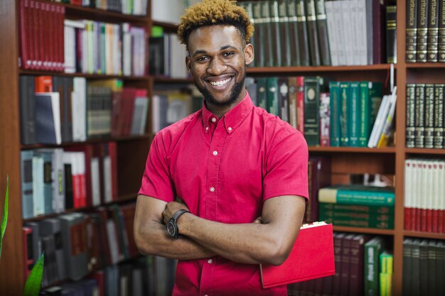 Sourire homme confiant avec livre dans la bibliothèque