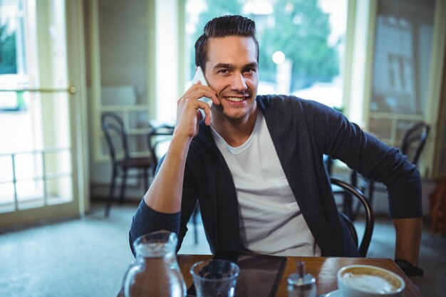 Sourire homme parlant au téléphone mobile dans cafÃ ©