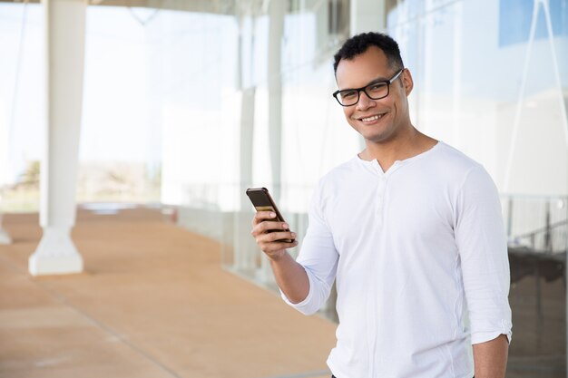 Sourire homme tenant le téléphone dans les mains, en tournant la tête à la caméra