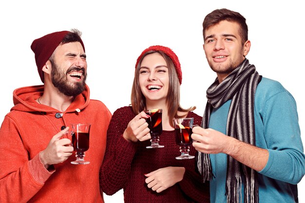 Sourire d'hommes et de femmes européens lors d'une séance photo de fête. Les gars se faisant passer pour des amis au studio fest avec des verres à vin avec du vin chaud au premier plan.