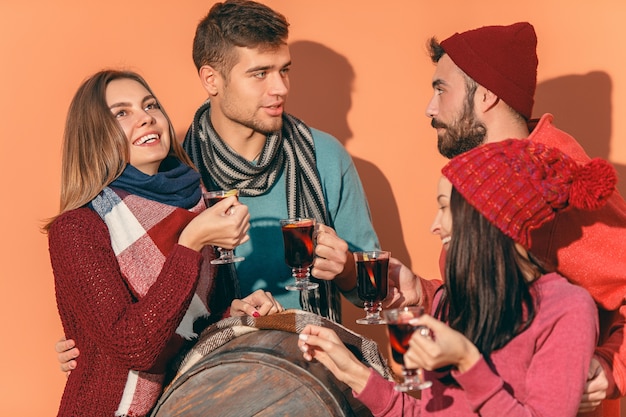 Sourire d'hommes et de femmes européens lors d'une séance photo de fête. les gars se faisant passer pour des amis au studio fest avec des verres à vin avec du vin chaud au premier plan.