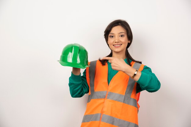 Sourire ingénieur femme tenant un casque sur fond blanc.