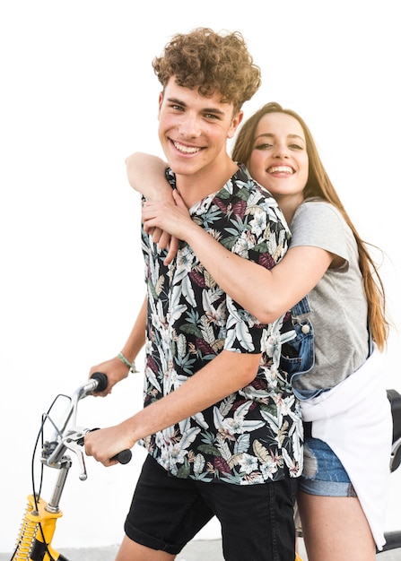 Sourire jeune couple assis sur une bicyclette sur fond blanc