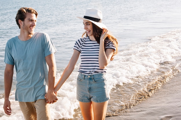 Sourire jeune couple se promenant à la plage