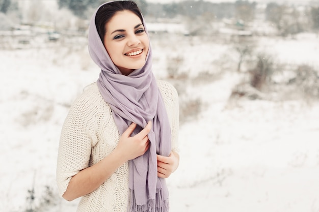 Sourire jeune femme couvrant sa tête et du cou