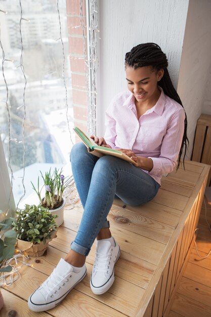 Sourire jeune femme jouissant d&#39;un livre préféré