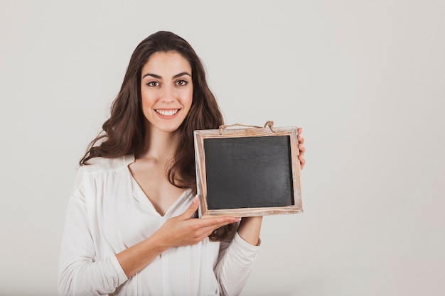 Sourire jeune femme tenant une ardoise vierge