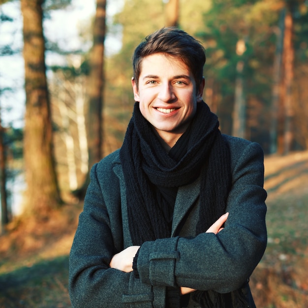 Sourire jeune homme avec les bras croisés en plein air