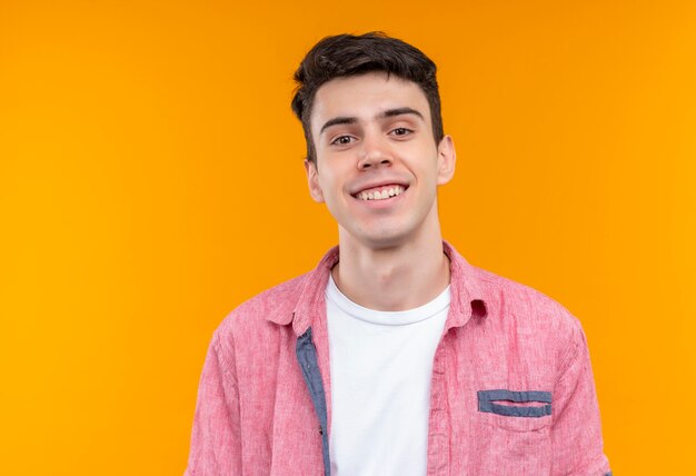 Sourire de jeune homme caucasien portant chemise rose sur fond orange isolé