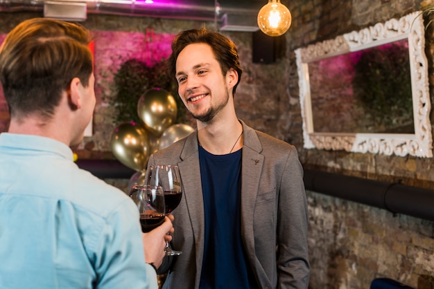 Sourire de jeunes amis célébrer et faire griller du vin au bar