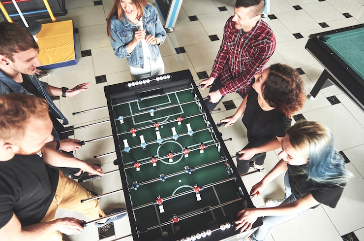 Photo gratuit sourire de jeunes jouant au baby-foot à l'intérieur