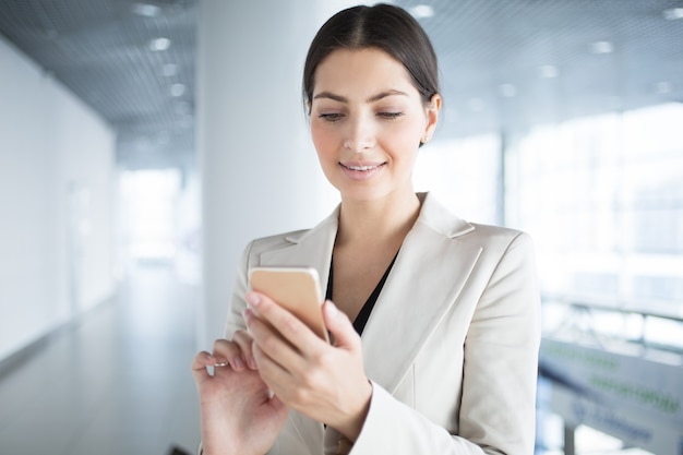 Sourire jolie femme d&#39;affaires utilisant un téléphone intelligent