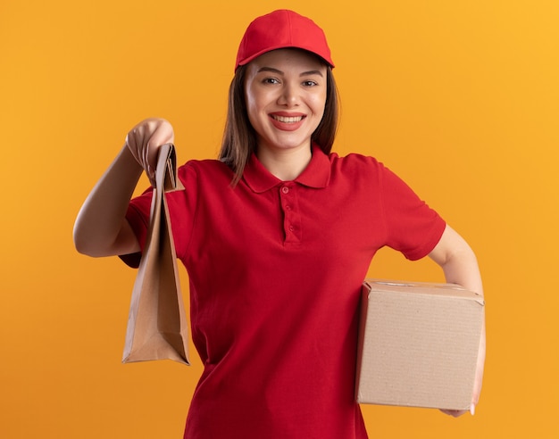 Sourire Jolie Femme De Livraison En Uniforme Détient Un Paquet De Papier Et Une Boîte En Carton Sur Orange