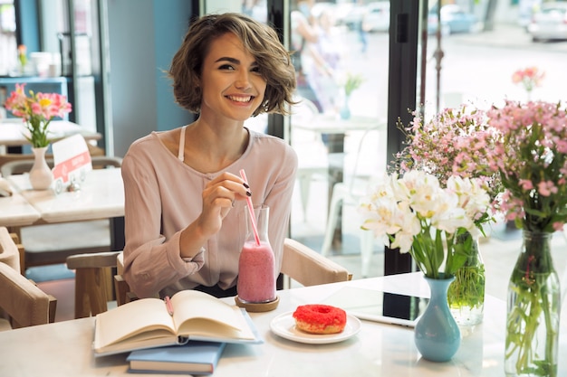 Sourire de jolie fille buvant un smoothie avec une paille