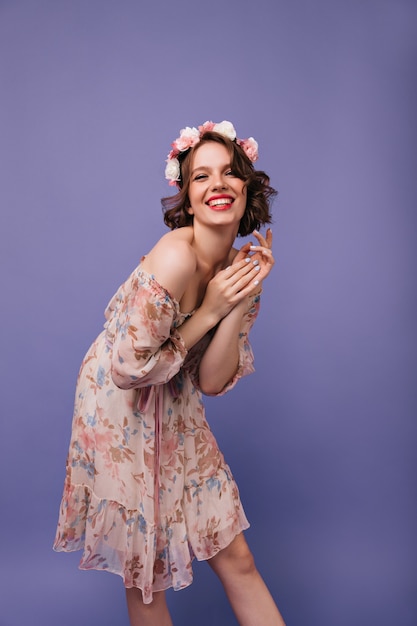 Sourire jolie fille avec des roses dans les cheveux debout. Adorable dame européenne en robe d'été dansant.