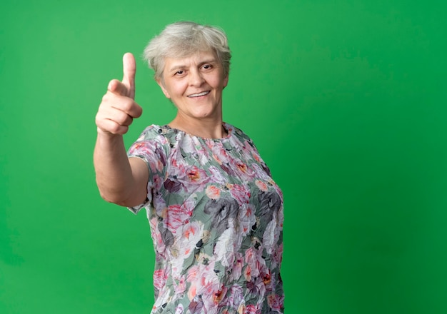 Sourire de points de femme âgée isolés sur mur vert