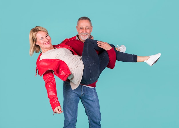 Photo gratuite sourire portrait d'une femme d'âge mûr portant sa femme sur fond turquoise