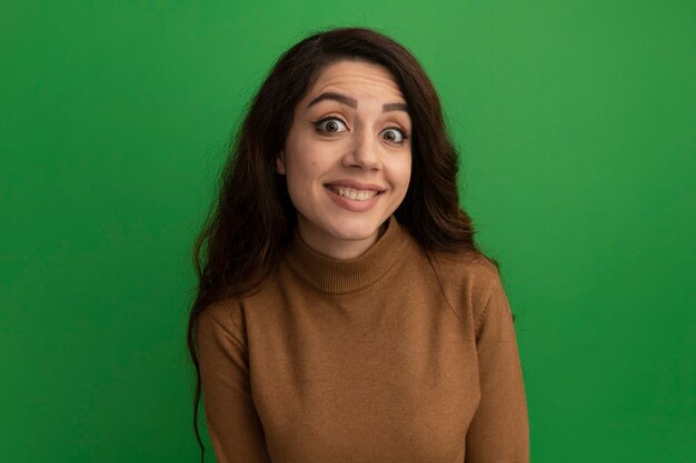 Sourire regardant devant jeune belle fille isolée sur le mur vert