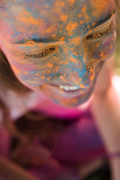 Sourire de visage de femme avec de la poudre de holi bleu et jaune