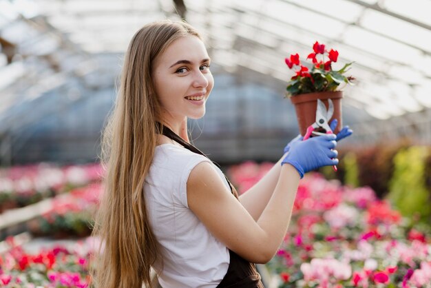 Sourire vue de côté femme tenant un pot de fleur